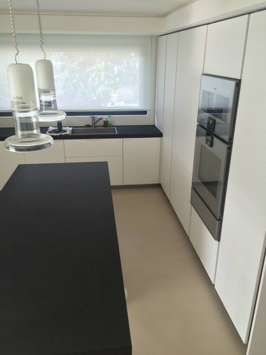 Béton ciré beige coulé dans une cuisine moderne blanche